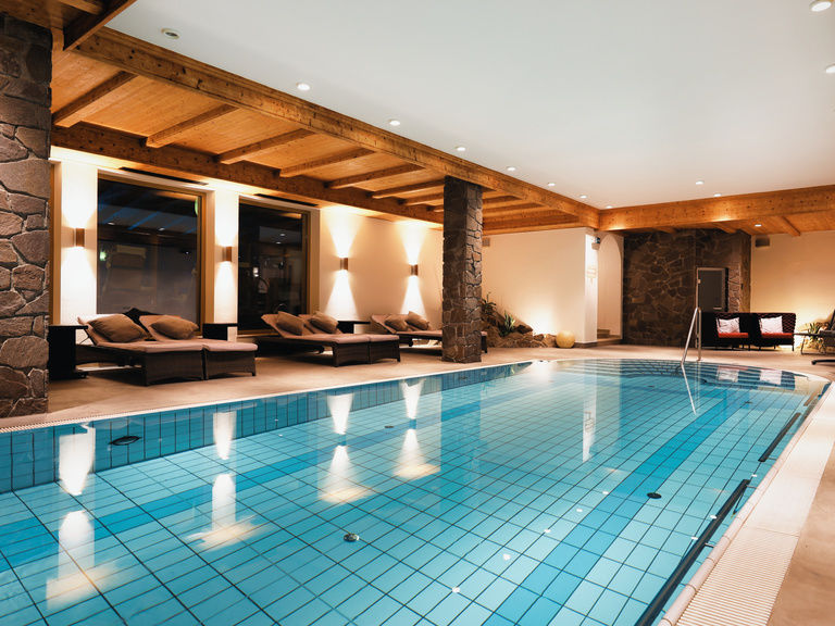 Wellnessbereich mit beleuchtetem Pool und Ruheliegen im Bayerischen Wald