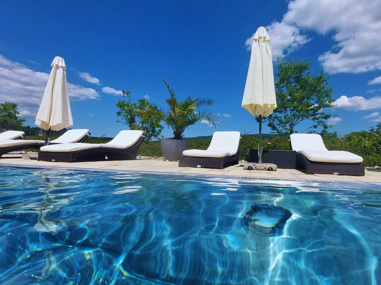 Außenpool mit Liegen und blauem Himmel im Wellnesshotel St. Gunther im Bayerischen Wald